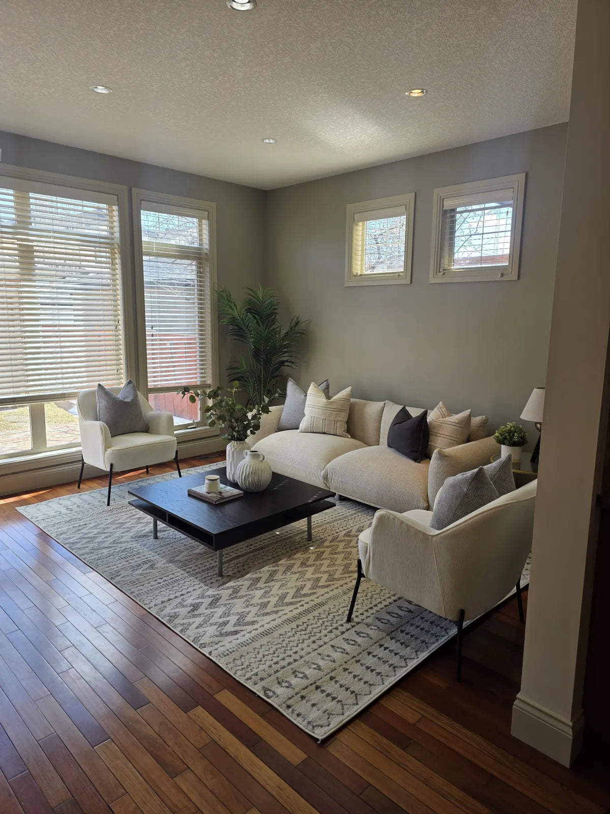 Living room staged with a sofa over warm hardwood flooring