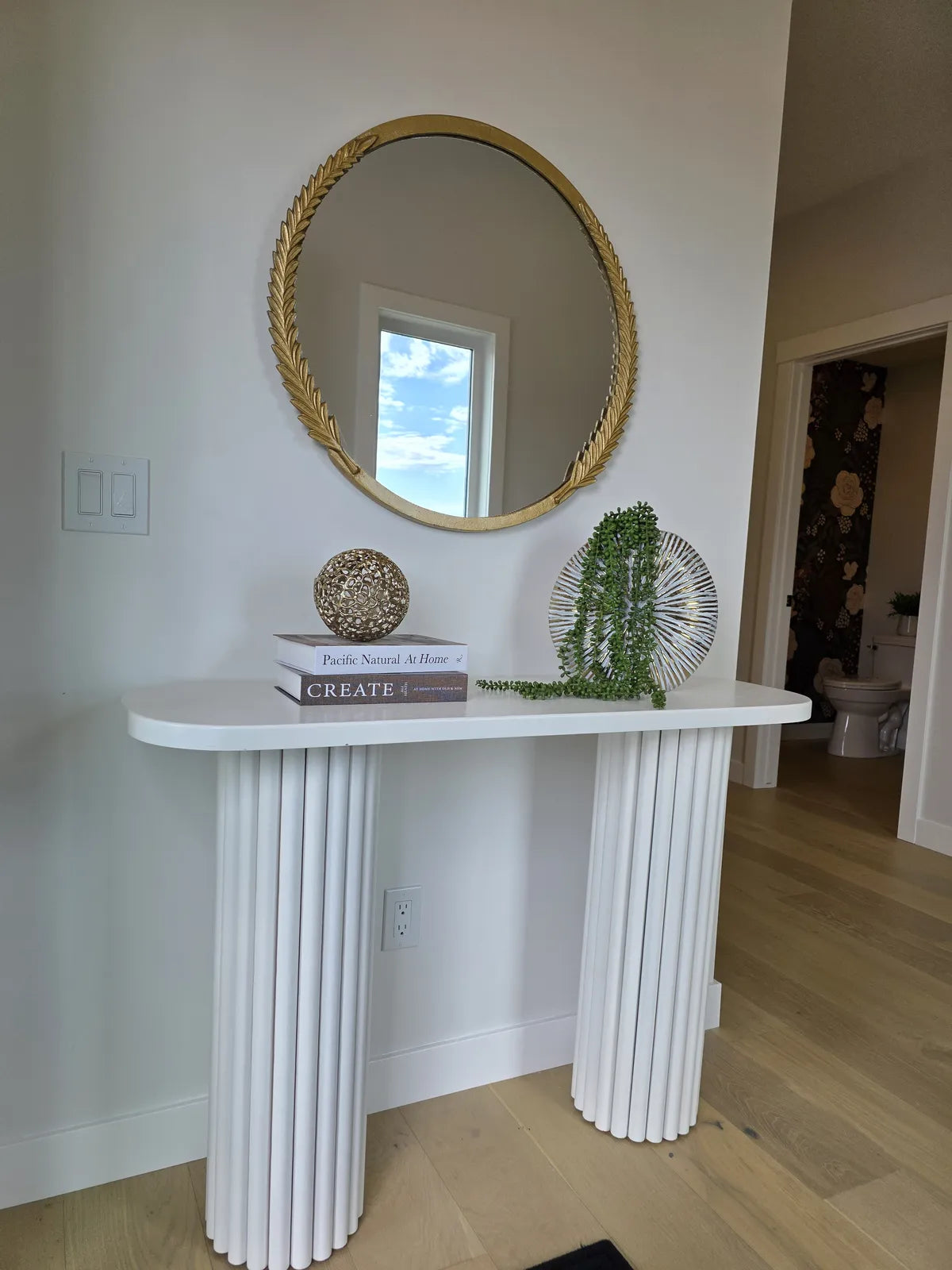 Entryway with a white console and round mirror