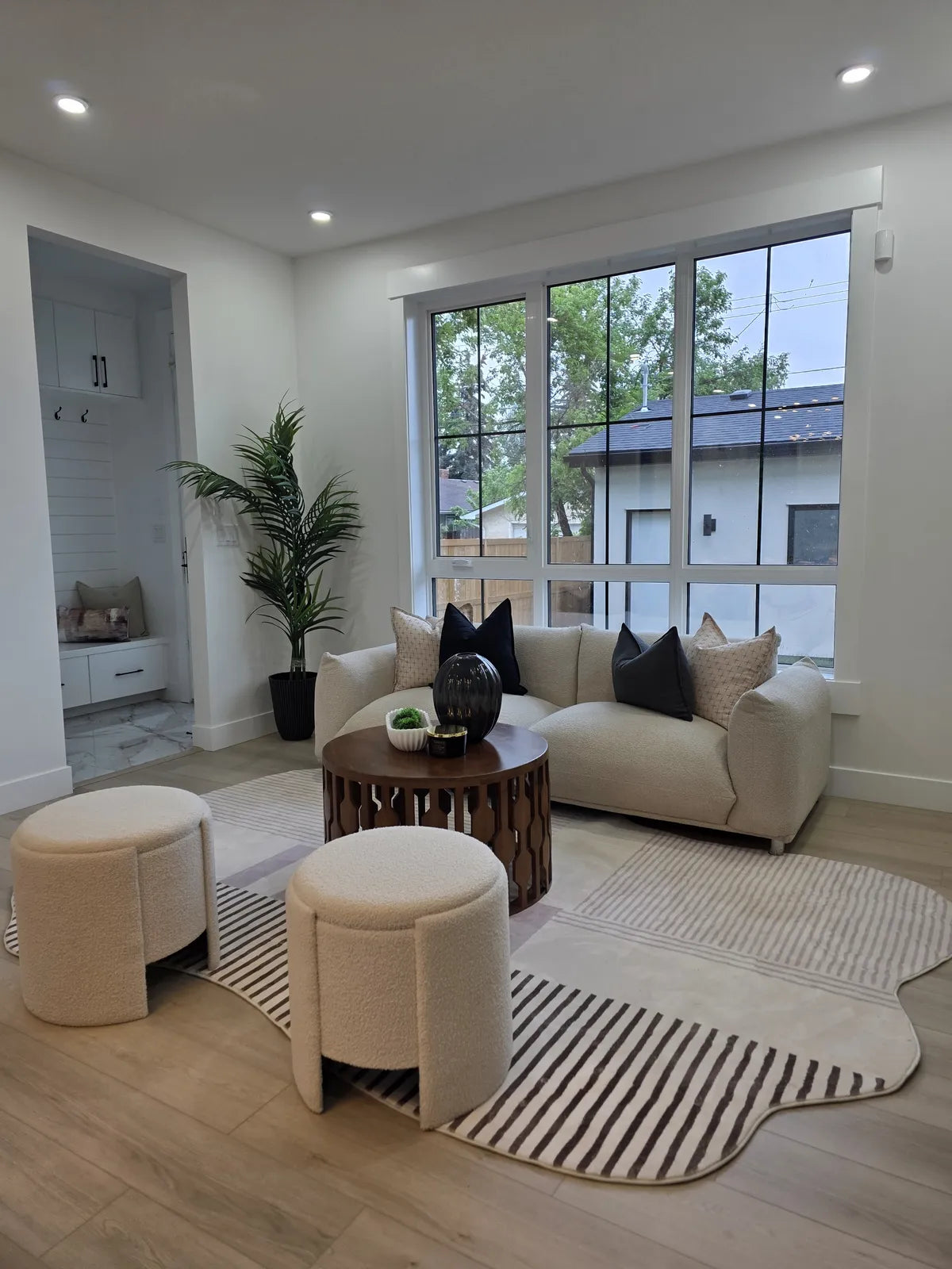 Living room staged with a patterned pouf beside a window