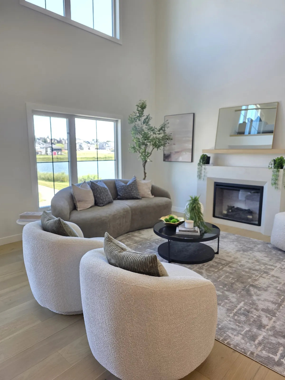 Living room staged with grey curved sofas beneath tall windows
